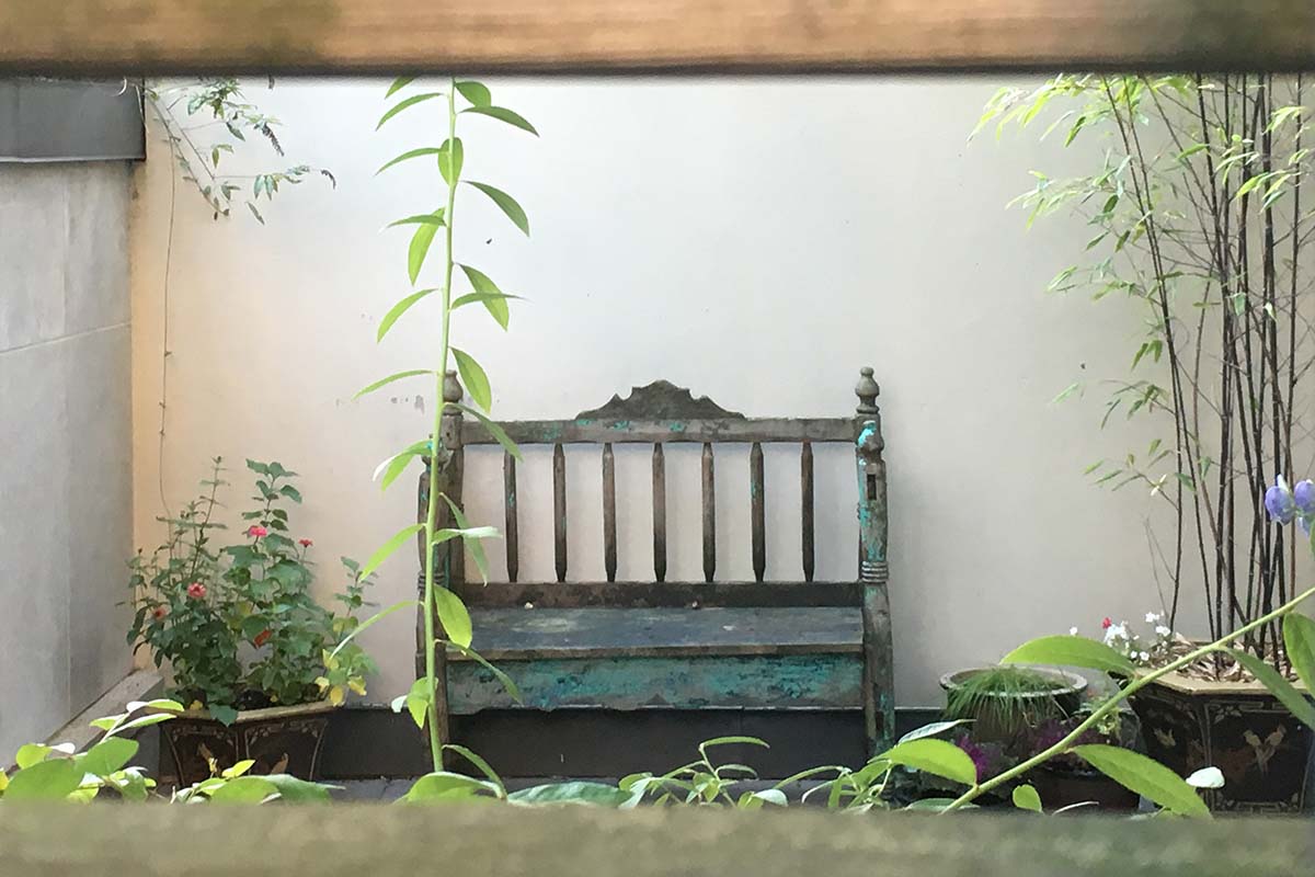 Antique wooden bench against cream wall in garden